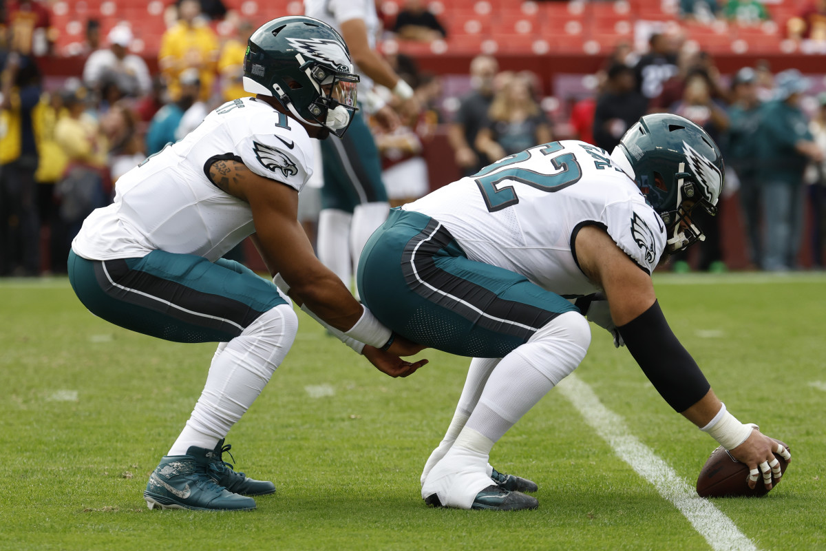 Jalen hurts kneels down to receive a snap from Jason kelce